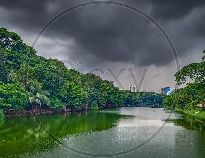 A Beautiful Lake In A Park Under The Cloudy Sky Surround By Beautiful Tree