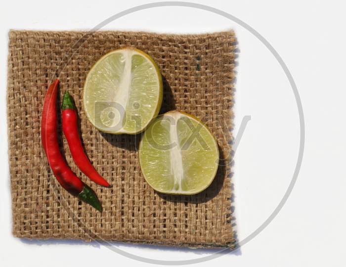 Lemon Slices With Chilies On Burlap Fabric Isolated On White Background