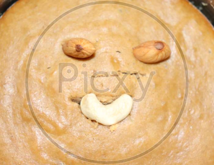 creepy looking face made on home cooked atta cake with almonds and cashews in steel bowl