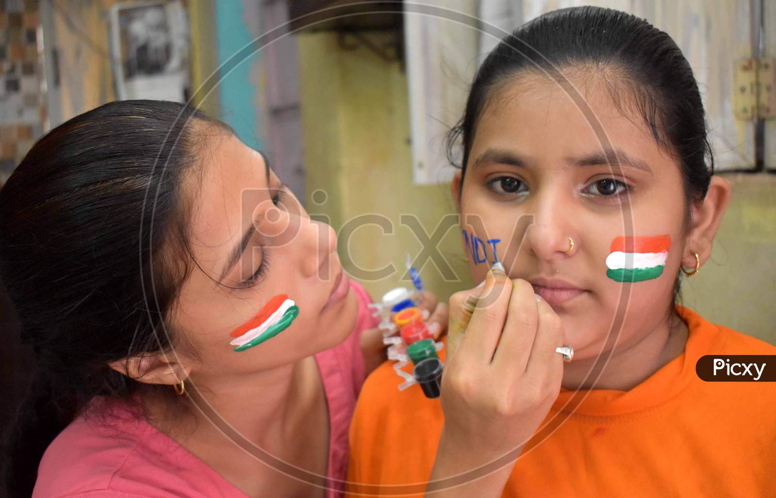 Girls paint their cheeks in tri-color national flag colours ahead of Independence day celebrations in Prayagraj, August 14, 2020.