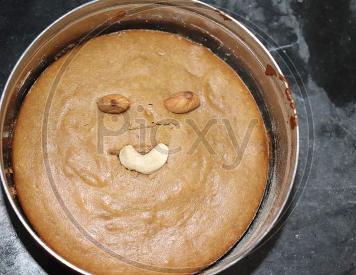 creepy looking face made on home cooked atta cake with almonds and cashews in steel bowl