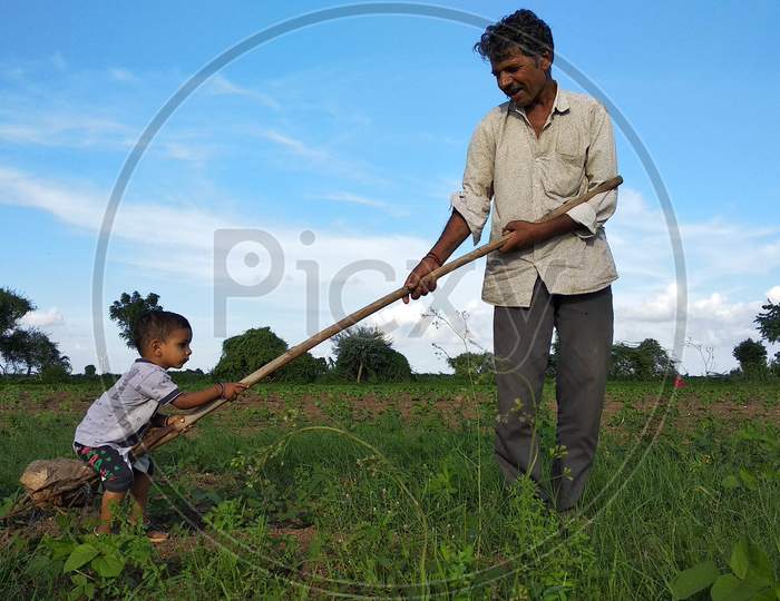 A young Indian child is having fun on a farm with his grandfather and uncle