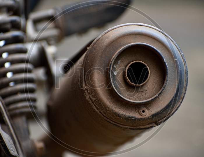 Close-up of a dirty bike silencer front view.