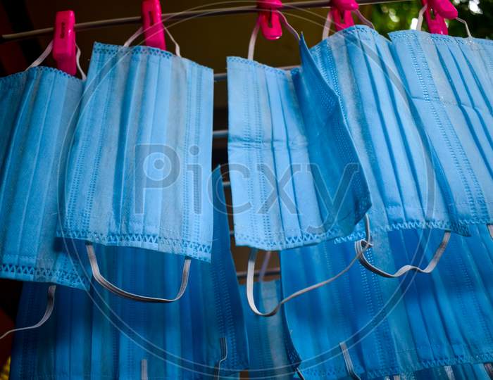 Corona Virus Pandemic Masks Being Hanged On A Cloth Rod After Cleaning. Reusable Blue Colored Face Masks
