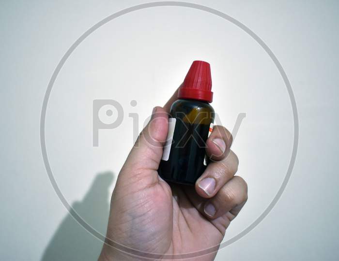 Homeopathic Medicine bottle in hand with isolated background.