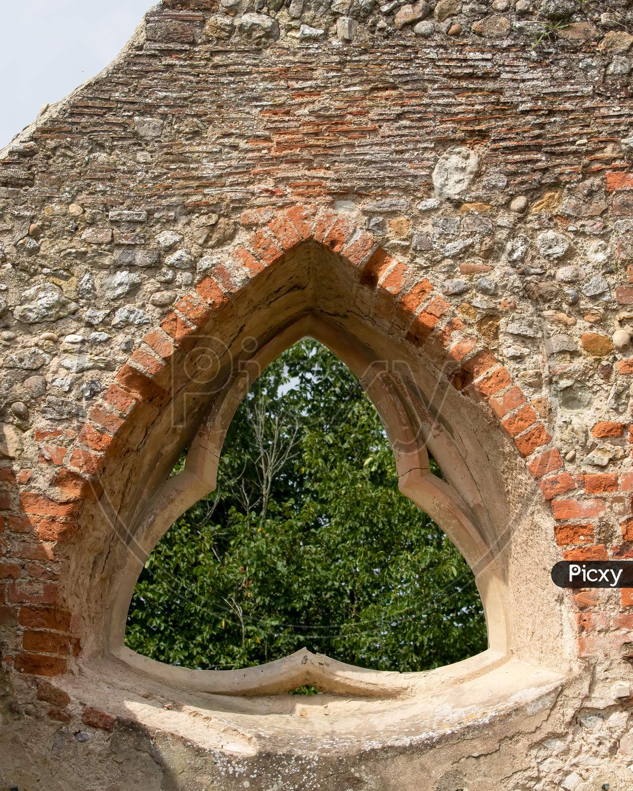 Church wall ruins with triangle window showing foliage behind