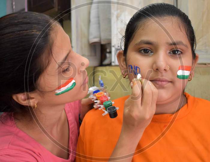 Girls paint their cheeks in tri-color national flag colours ahead of Independence day celebrations in Prayagraj, August 14, 2020.