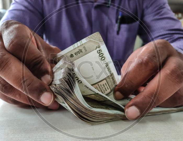 Man Counting Indian Currency With Hands.