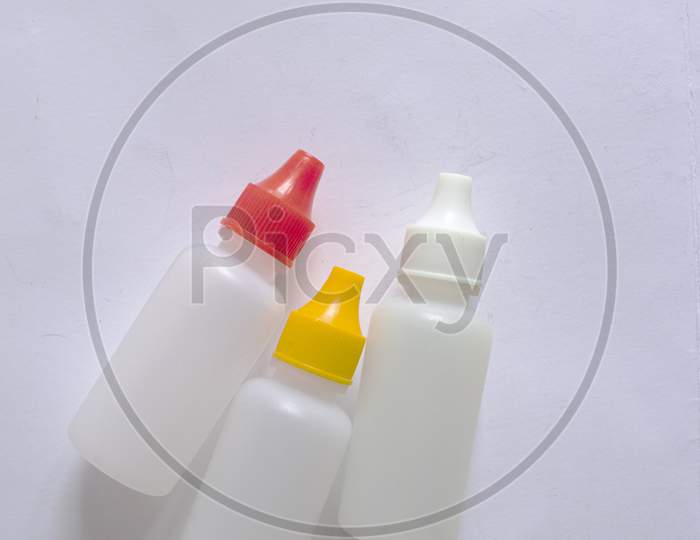Three Small White Bottles With White, Red And Yellow Cap On White Background.