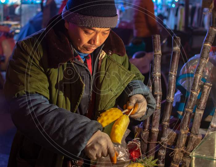 Man Cutting And Selling Pineapple On Street Food Fruit Stall In Luoyang, China