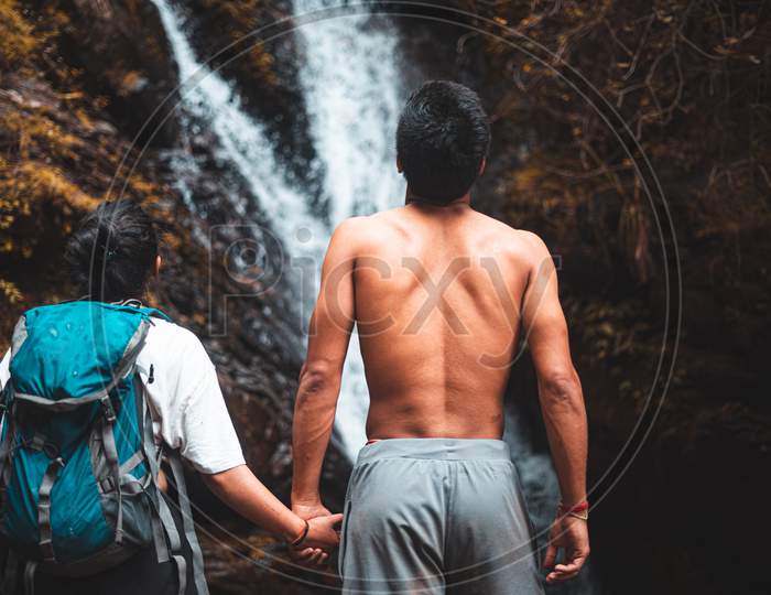 Young Couple Enjoying The Beautiful Waterfall View.