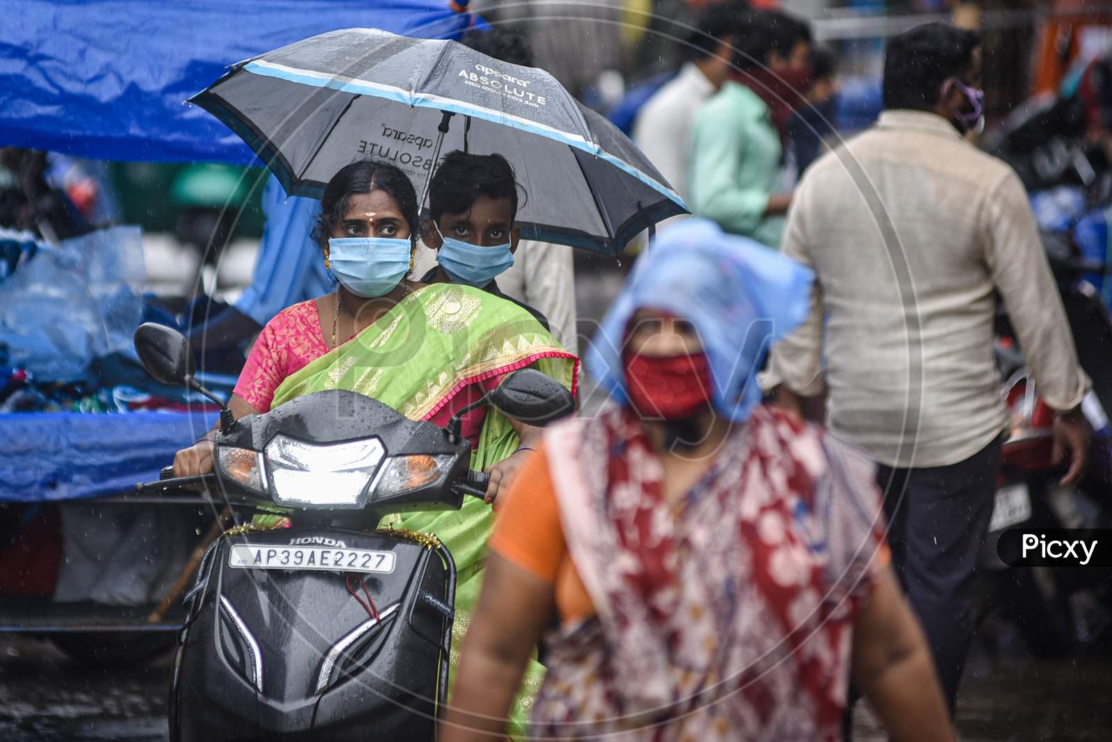 People Take Shelter Under An Umbrella While Riding A Vehicle, During The Rain, At Besant Road, In Vijayawada On August 15, 2020.