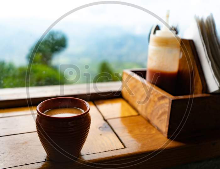 A Kullad Full Of Tea Kept On The Window With A Great View Of Mountains.