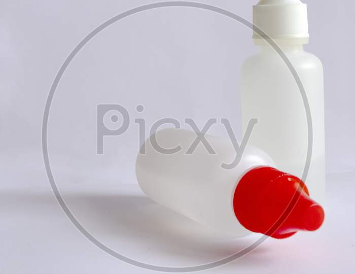 Two Small White Bottles With One White Cap And One With Red Cap On White Background.