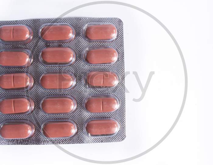 Brwon Coloured Pills In Plastic Packaging With Negative Space Provided.