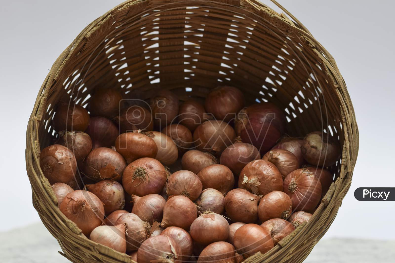Small Onions Stored In Round Brown Wicker Bamboo Basket In Indian And Pakistani Household.
