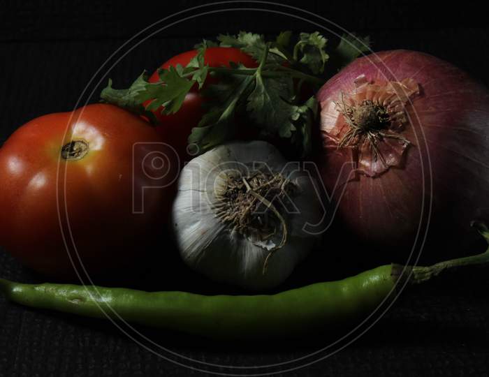 Green Chilly, Garlic, Tomato And Curry Leaf Are Isolated On Black Background. Ingredients Concept. Hot And Spicy Green Chillies And Fresh Ripe Tomato On Black Background.
