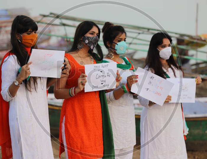 Women hold posters with messages to celebrate Independence day on the river bank of Sangam in Prayagraj, August 15, 2020.