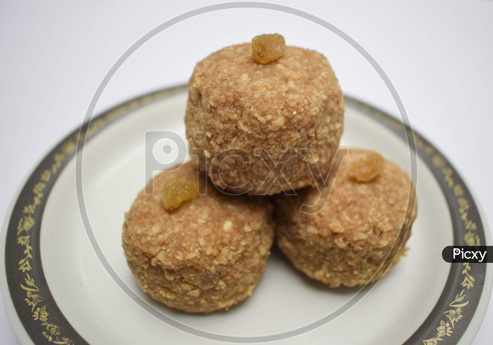 Closeup Of Popular Indian Sweet Balls Laddu Or Ladoo Made From Chapati Roti Powdered Mashed And Made In To Big Ball. Decorated With Raisin Kismis Served In Plate. Prashad For Festivals