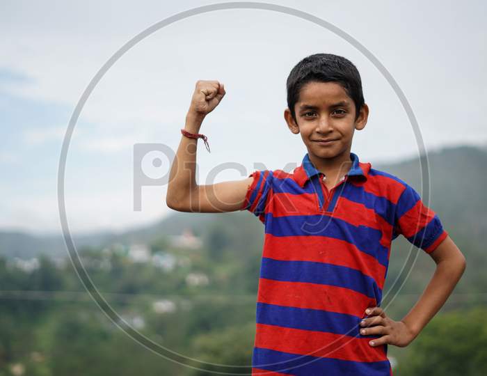 Young Indian Kid Showing His Biceps While Smiling Into The Camera.