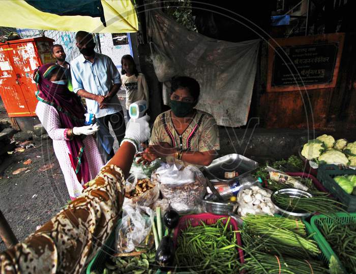 A healthcare worker checks the temperature of a vegetable vendor during a check up camp for the coronavirus disease (COVID-19), in Mumbai, India on August 15, 2020.