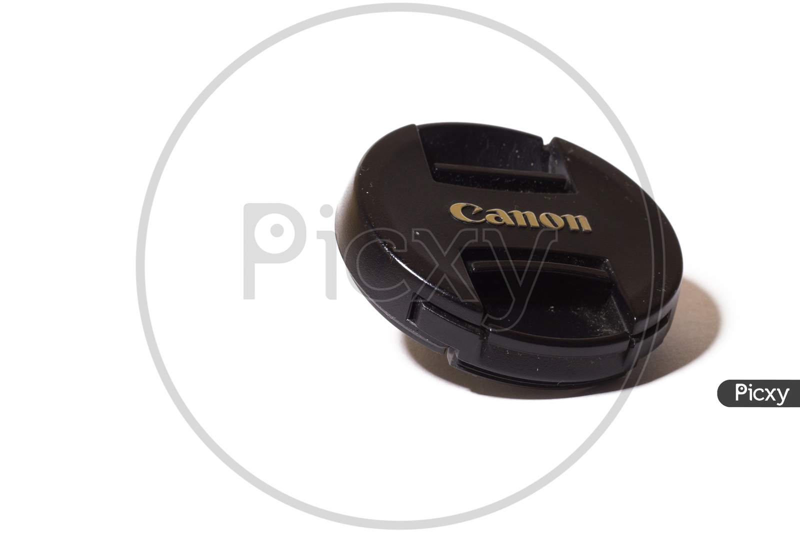 Black Lens Cap Isolated On White Background. Canon Logo On Camera Accessory