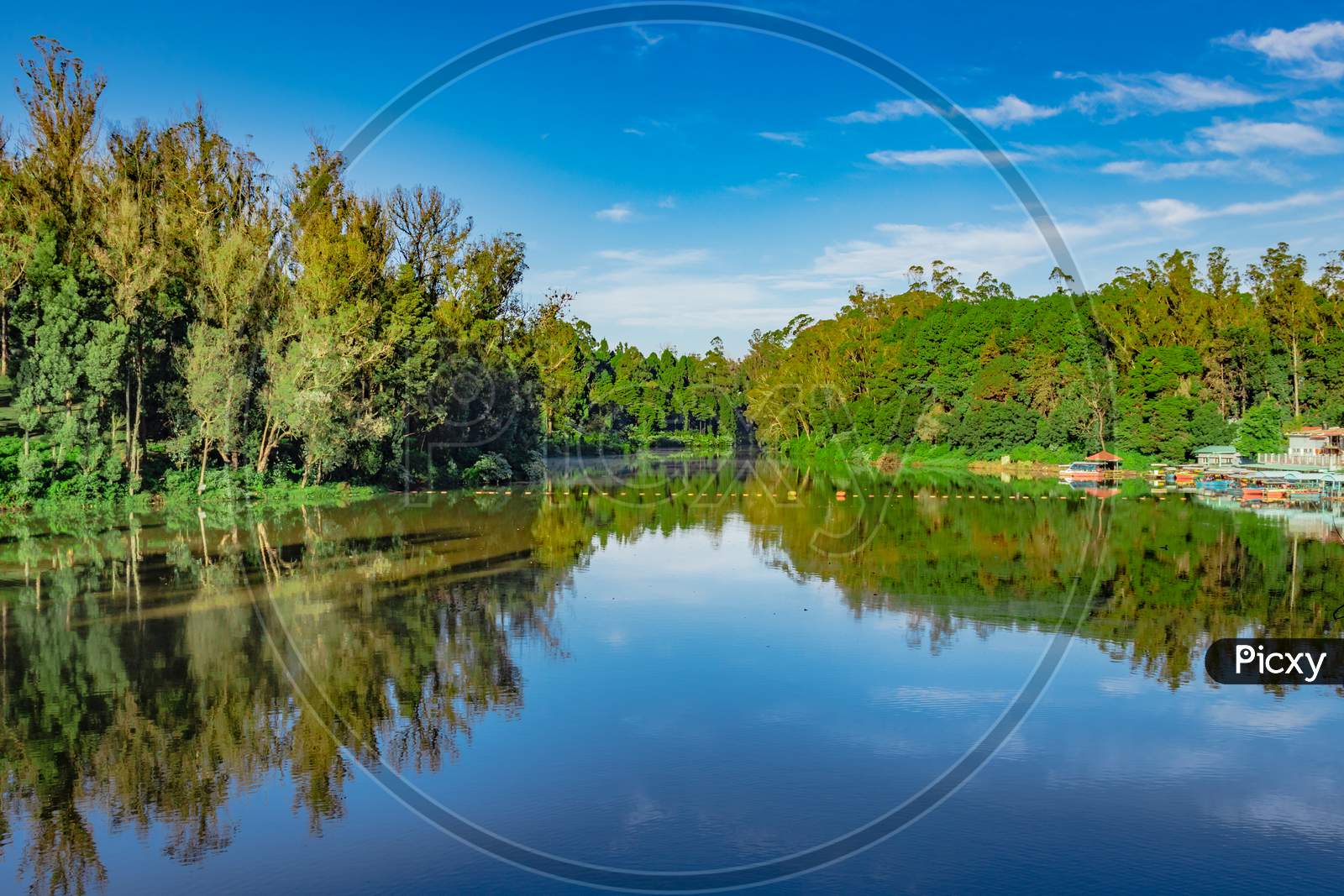 Lake Pristine With Green Forest Water Reflection And Bright Blue Sky At Morning