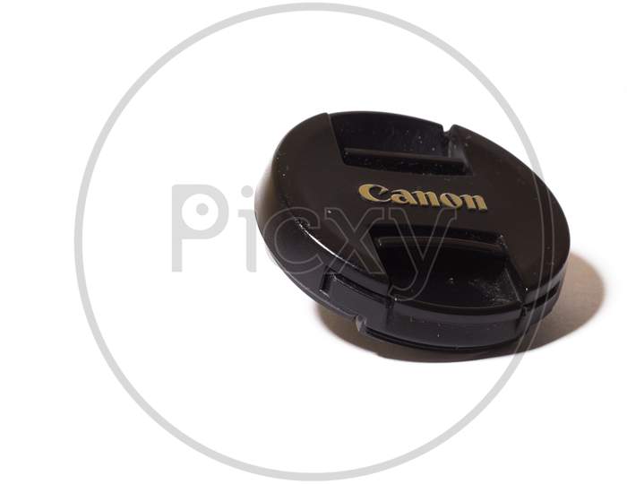 Black Lens Cap Isolated On White Background. Canon Logo On Camera Accessory