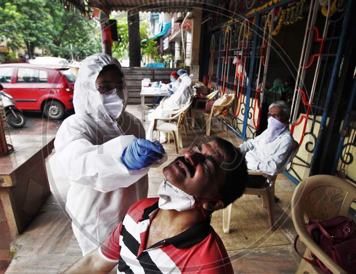 A healthcare worker wearing personal protective equipment(PPE) collects a swab sample from a resident during a check up camp for the coronavirus disease (COVID-19), at the entrance of a temple, in Mumbai, India on August 15, 2020.