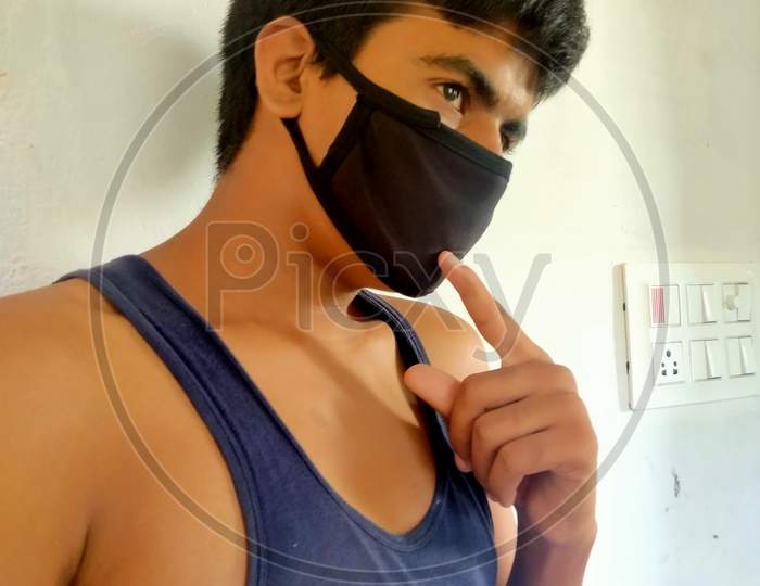 An Indian teen indicating his face mask during covid 19 pandemic