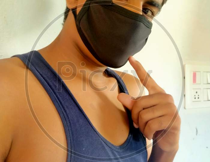 An Indian teen indicating his face mask during covid 19 pandemic