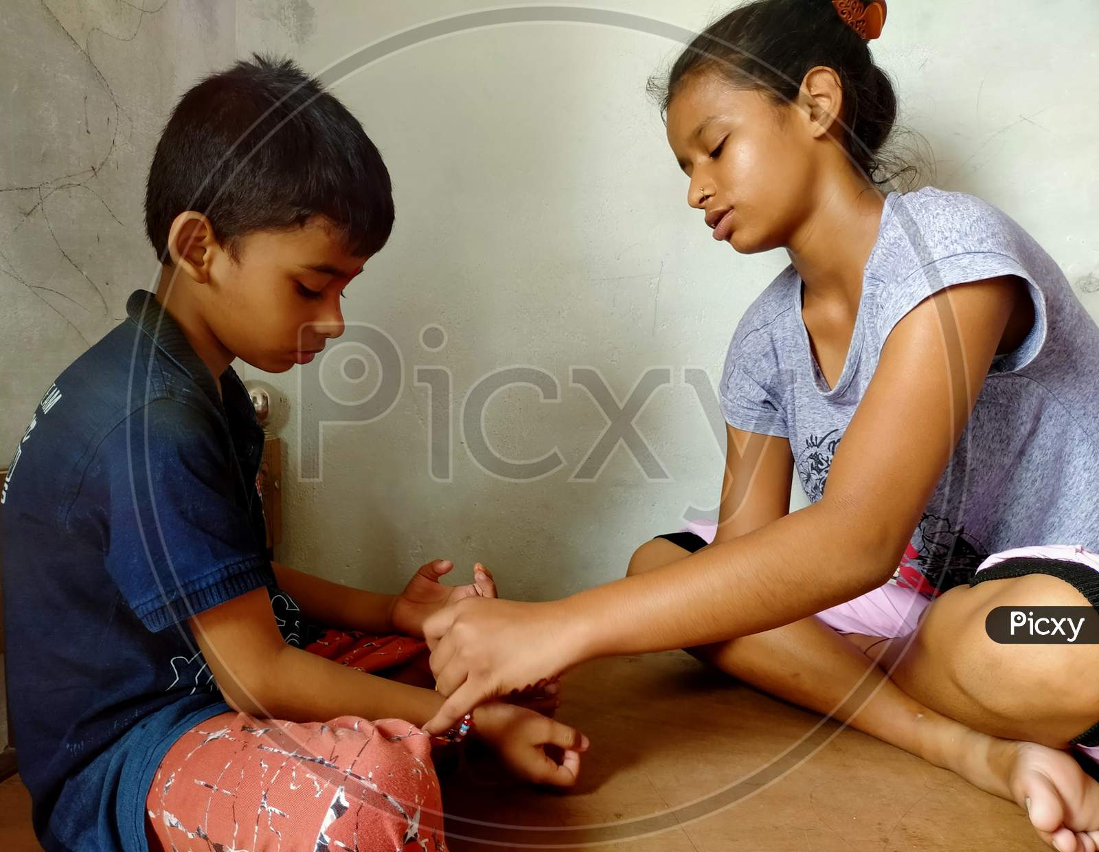 An Indian sister tieing Rakhi on hand of her brother