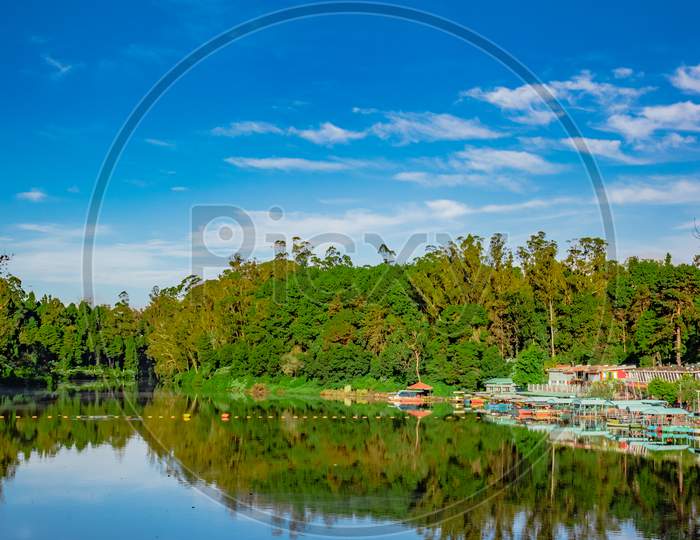 Lake Pristine With Green Forest Water Reflection And Bright Blue Sky At Morning