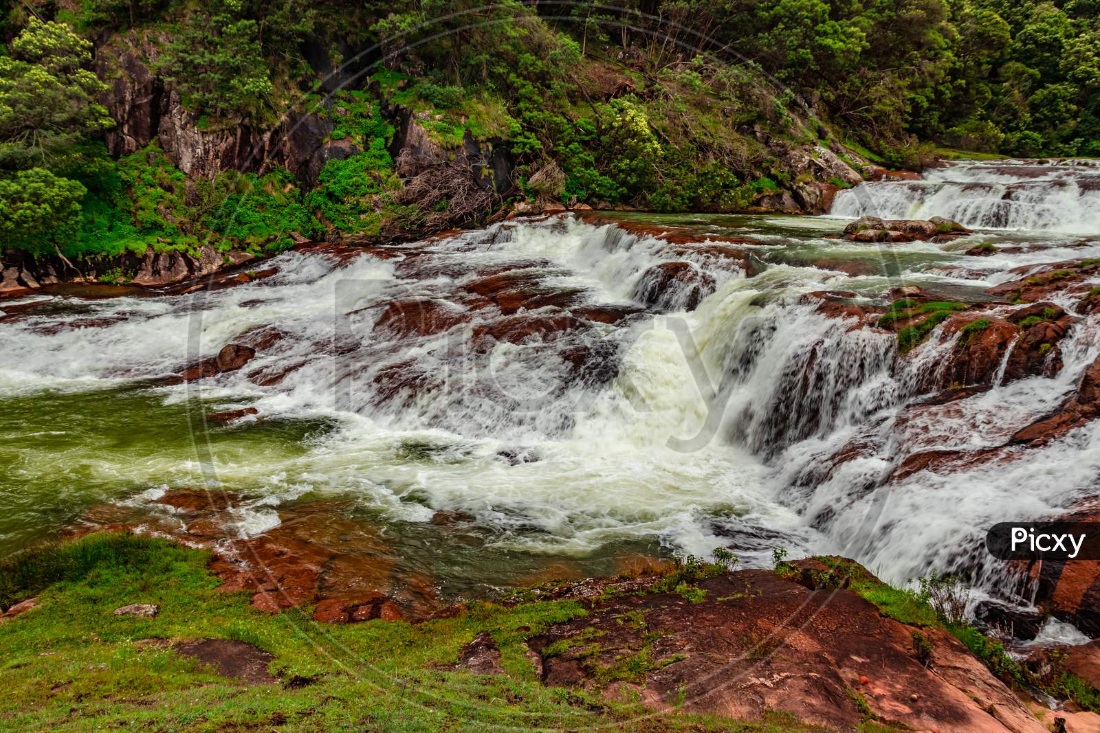 Waterfall With Red Rock And Green Lush Forest Flat Angle Shot