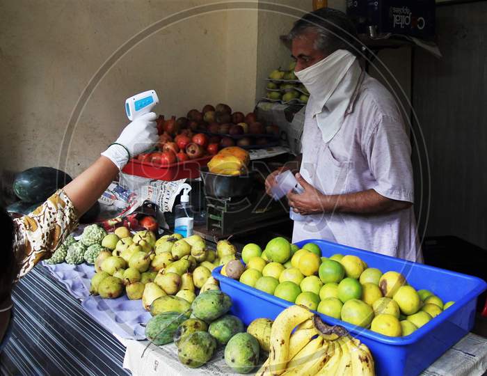 A healthcare worker checks the temperature of a vegetable vendor during a check up camp for the coronavirus disease (COVID-19), in Mumbai, India on August 15, 2020.