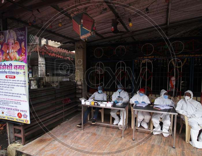 Healthcare workers in personal protective equipment (PPE) wait for people during a check up campaign for the coronavirus disease (COVID-19), at the entrance of a temple, in Mumbai, India on August 15, 2020.