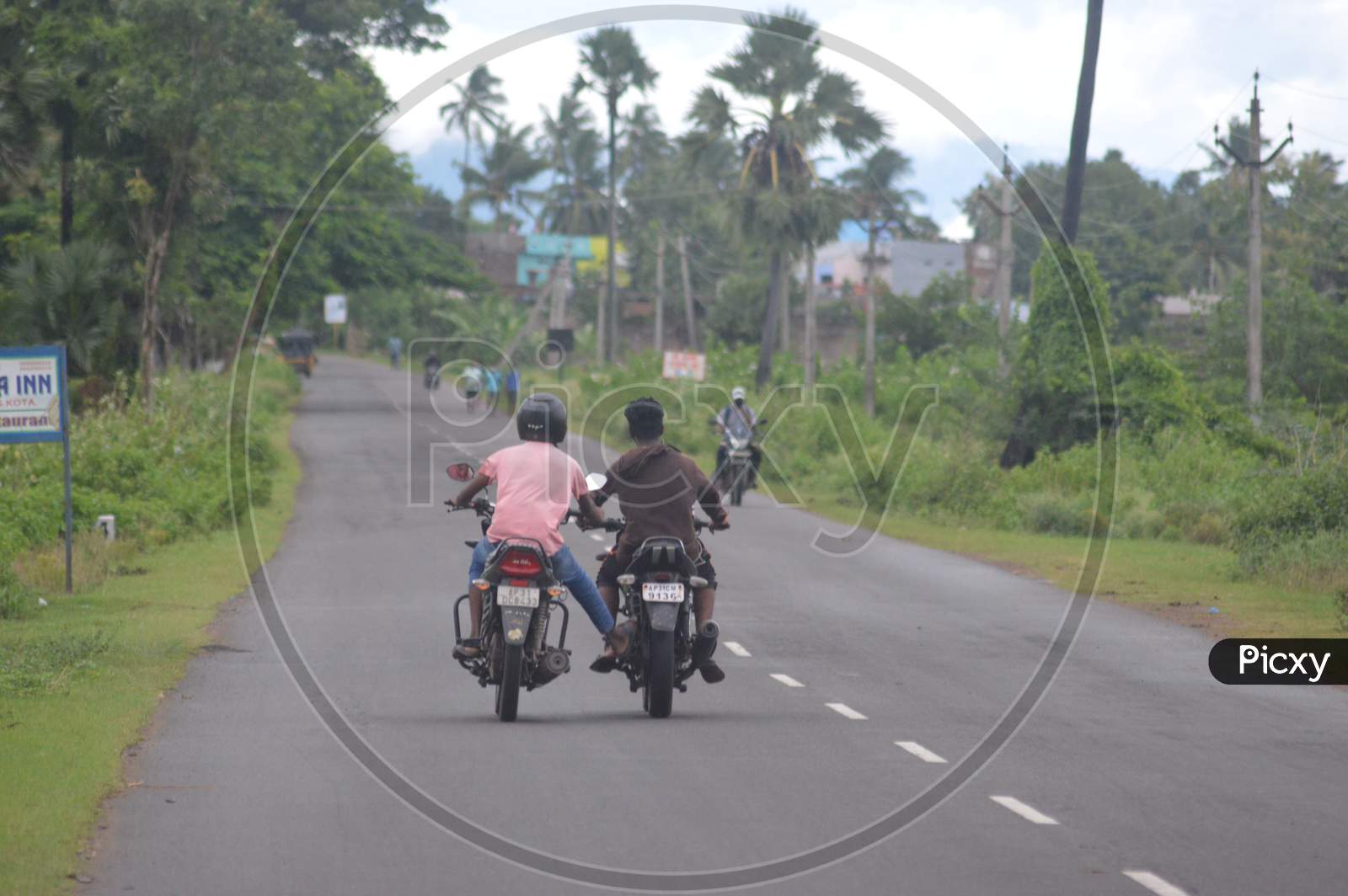 A motorcyclist helping other motorcyclist when out of fuel in Indian village roads