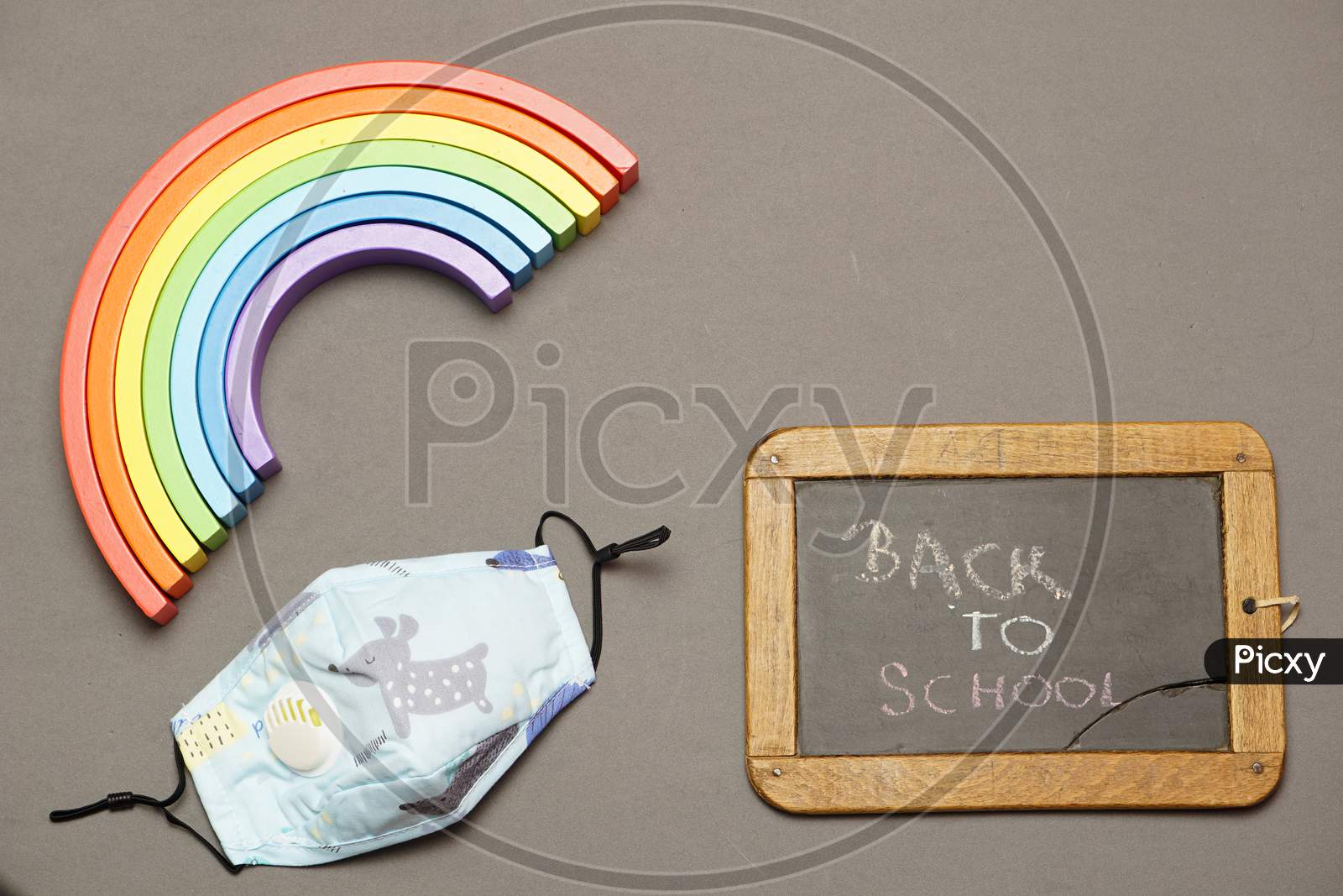 Top View Of Blackboard With Face Mask With Back To School Message And Rainbow. Back To School Concept With Covid 19. Flat Lay. Flat Design