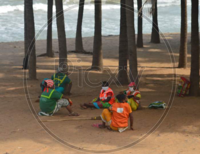 Indian sanitation workers relaxing after lunch under the trees on a sunny day