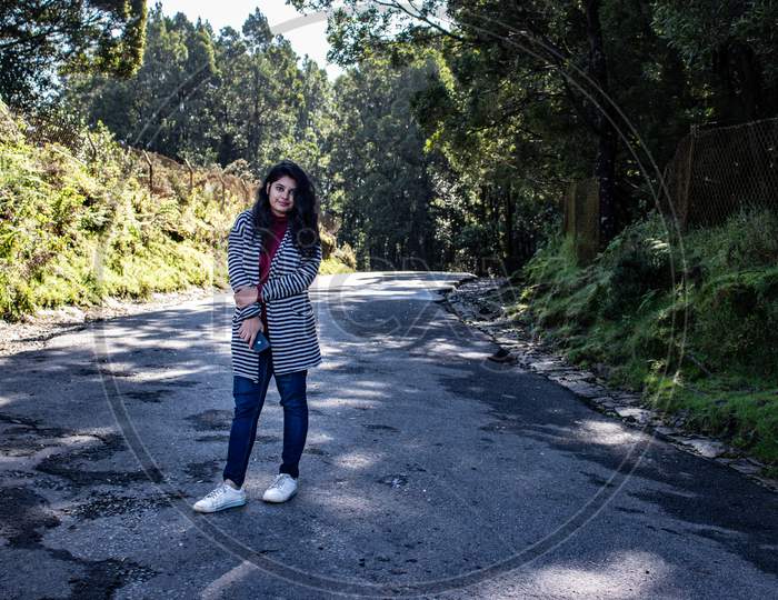 Girl Isolated At Tarmac Road With Green Forest Background