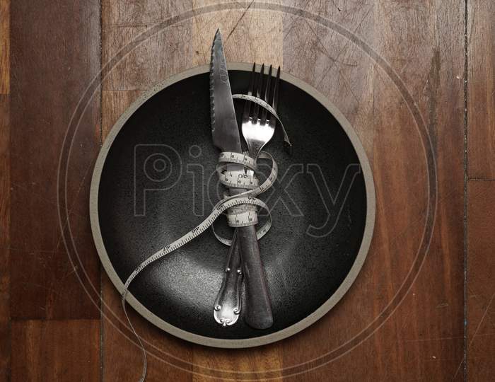 Empty Plate On Wooden Background With Cutlery And Measuring Tape. Diet Concept.Flat Lay