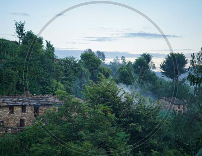 Landscape Of A Village Covered With Green Trees Captured In The Evening.