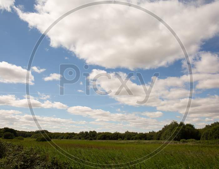 English Countryside water meadow under cloudy blue skies