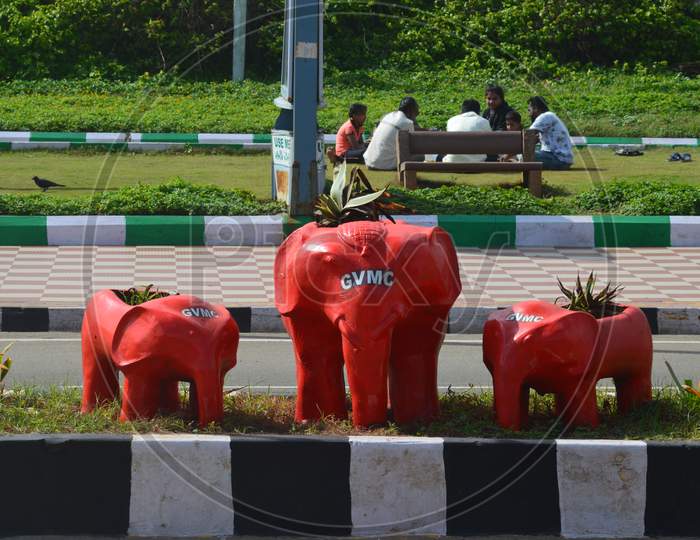 Red painted elephant shaped plant pots decorated in between Indian roads