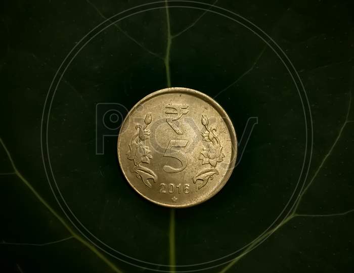 A five rupee coin over a leaf