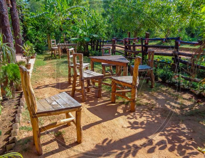 Wooden table and chairs in the small meadow surrounding with green Nature, at Shantiniketan, West Bengal