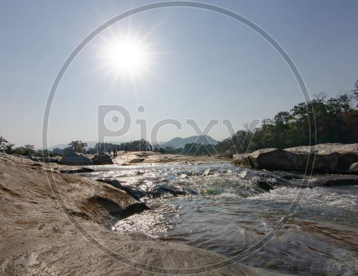 Natural dam with sun burst in the sky