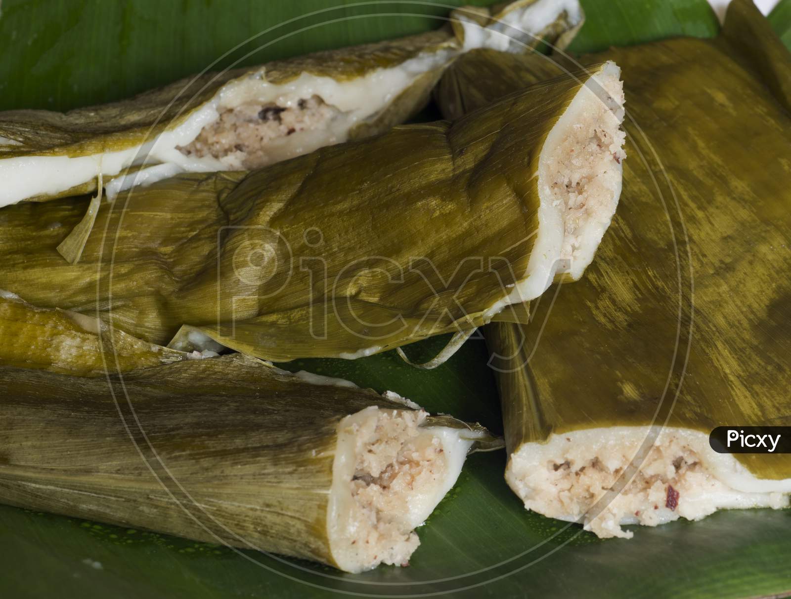 Indian Sweet Called Patholis Made Of Steamed Rice Flour Filled With Jaggery, Cardamom And Coconut. Wrapped In Turmeric Leaves And Steam Cooked In Large Vessel.