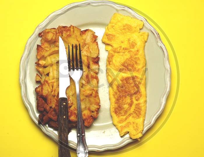 Roasted Or Fried Potatoes And Omelette On A Green Plate With Cutlery On Top. Food Concept. Flat Lay. Plain Design