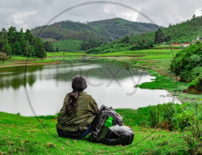 Girl Isolated Sitting At Serene Lake With Lush Green Forest